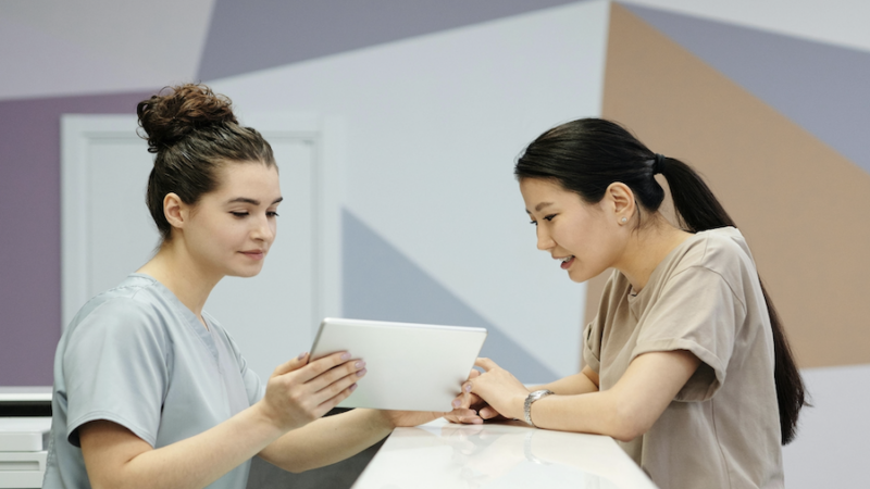 two people ipad reception talking patient clinic