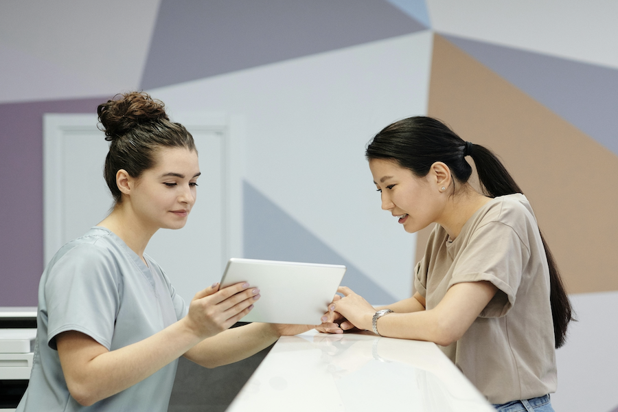 two people ipad reception talking patient clinic