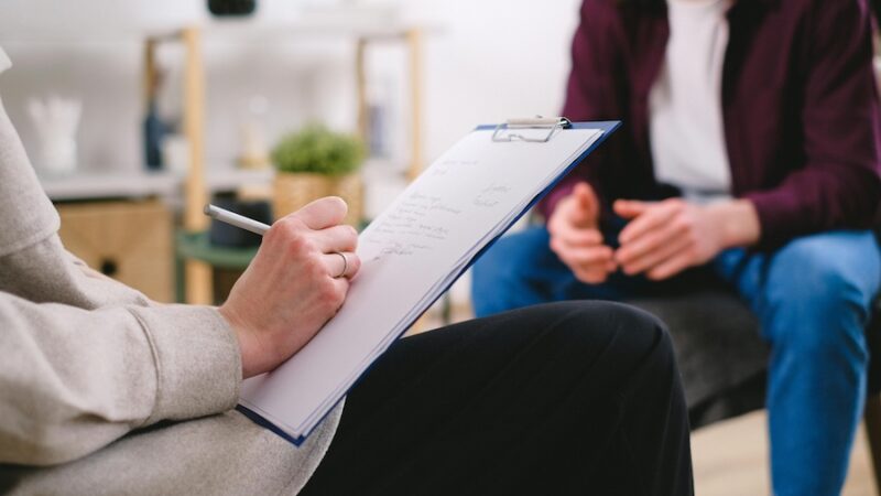 two people consultation counselling clipboard writing pen