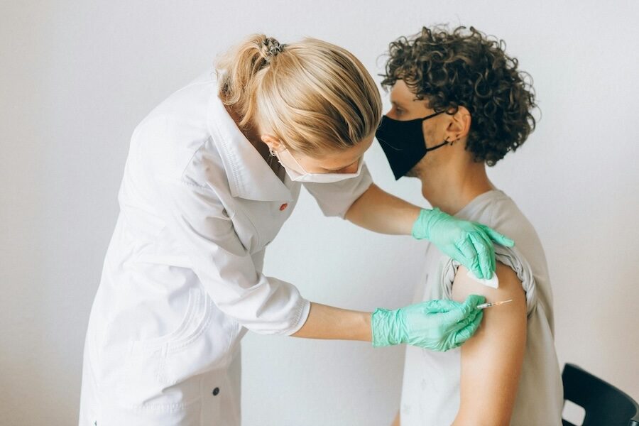 healthcare professional injecting patient arm sitting down