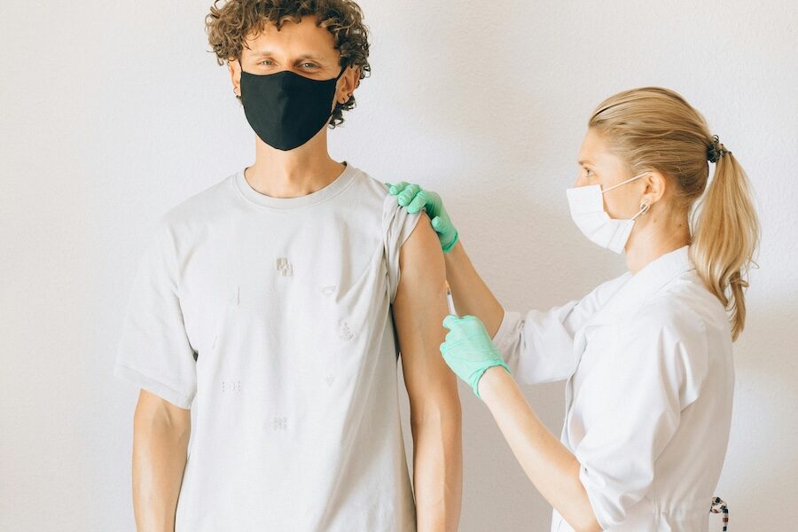 healthcare professional injecting patient with needle face masks