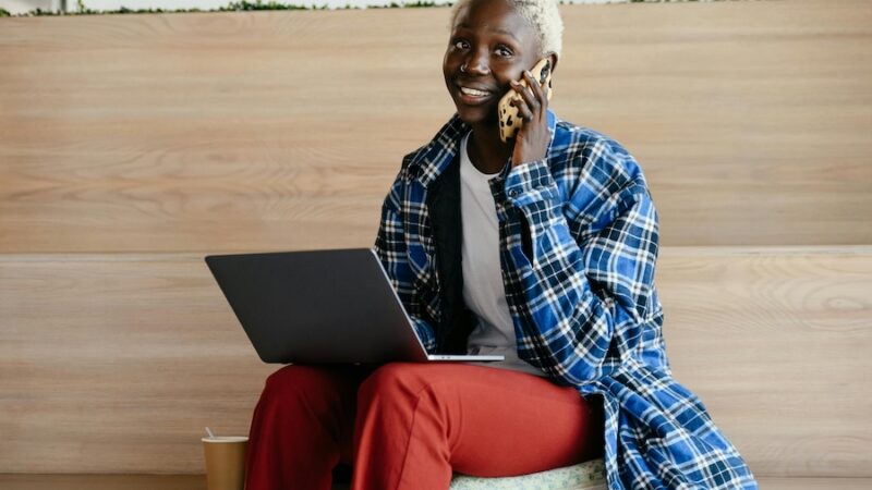 person on laptop and speaking on mobile phone