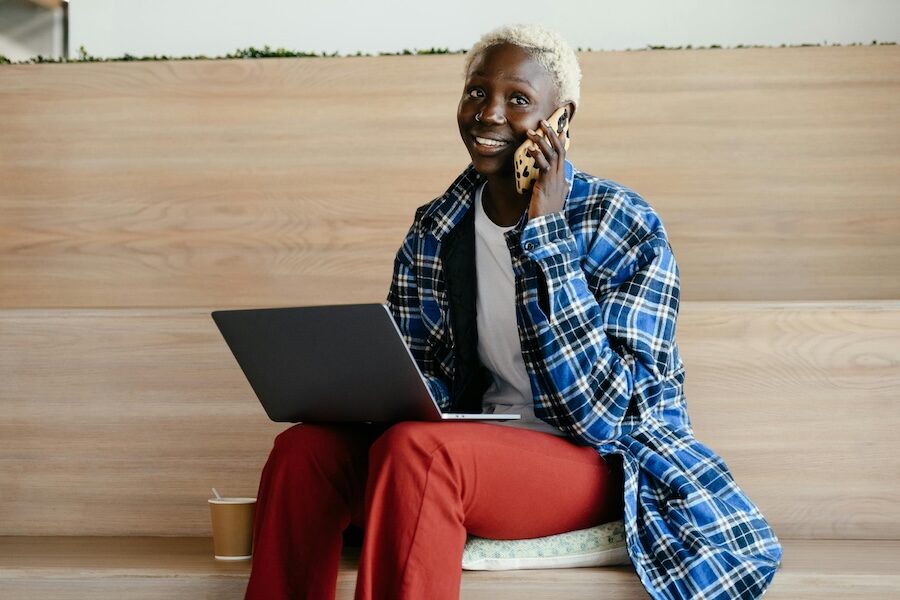 person on laptop and speaking on mobile phone