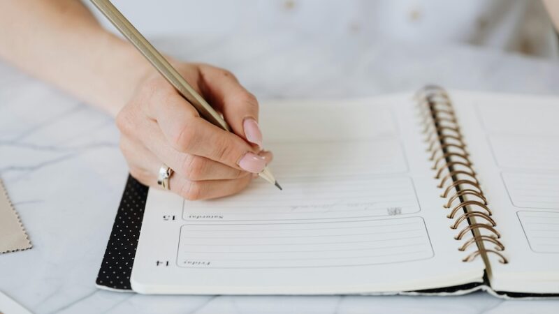 person writing in diary calendar