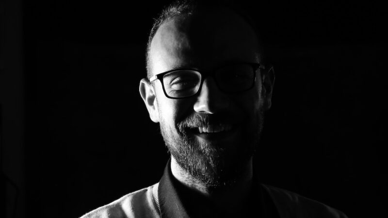 smiling person wearing glasses black and white