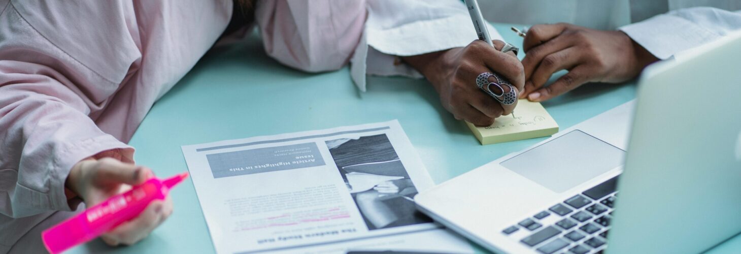 two people taking notes post-it pink highlighter