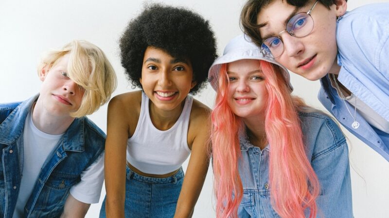 four young people smiling pink hair blue denim