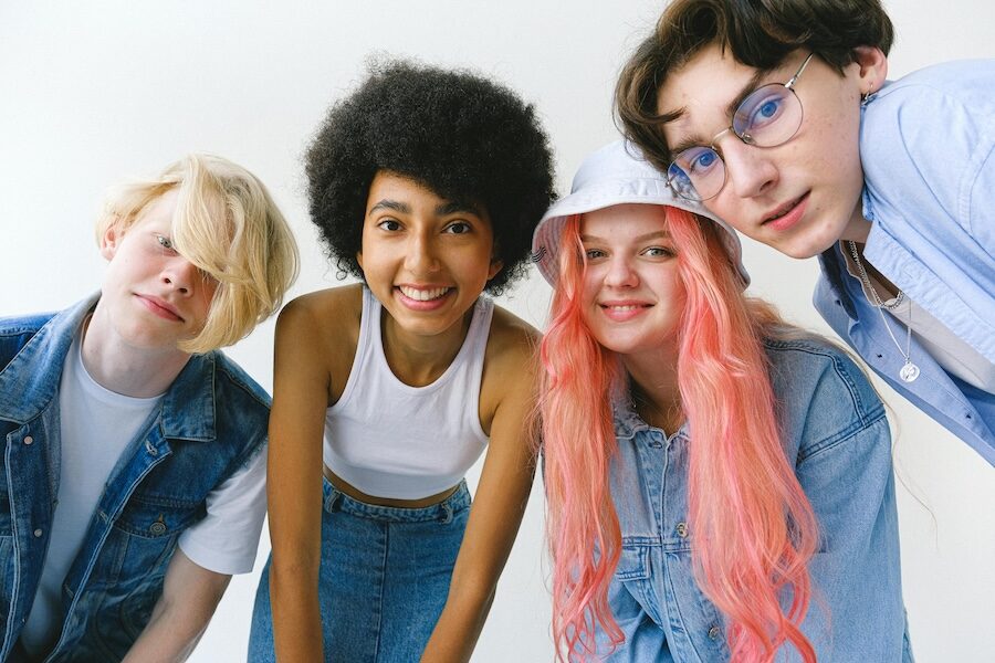 four young people smiling pink hair blue denim