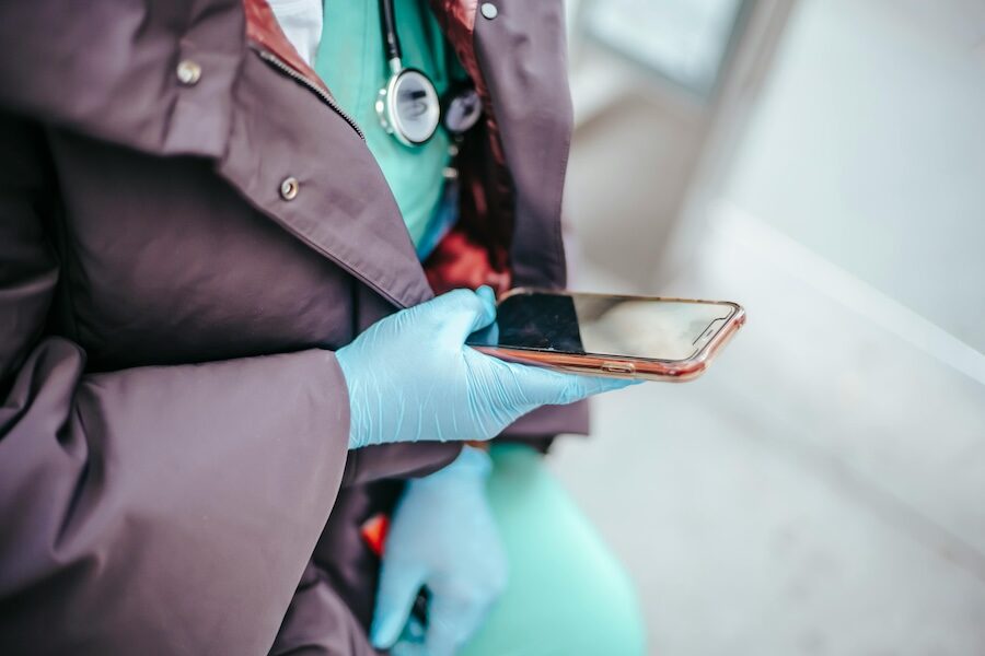 healthcare professional on mobile phone wearing latex gloves