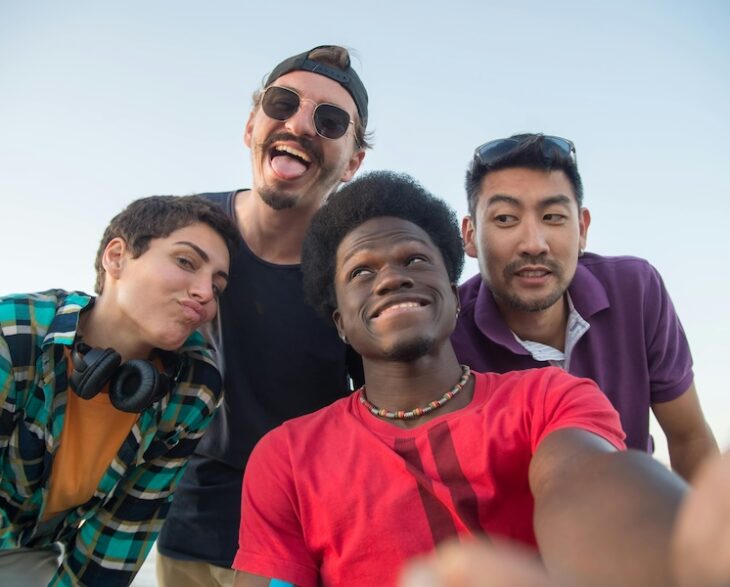 four smiling people outside pulling faces