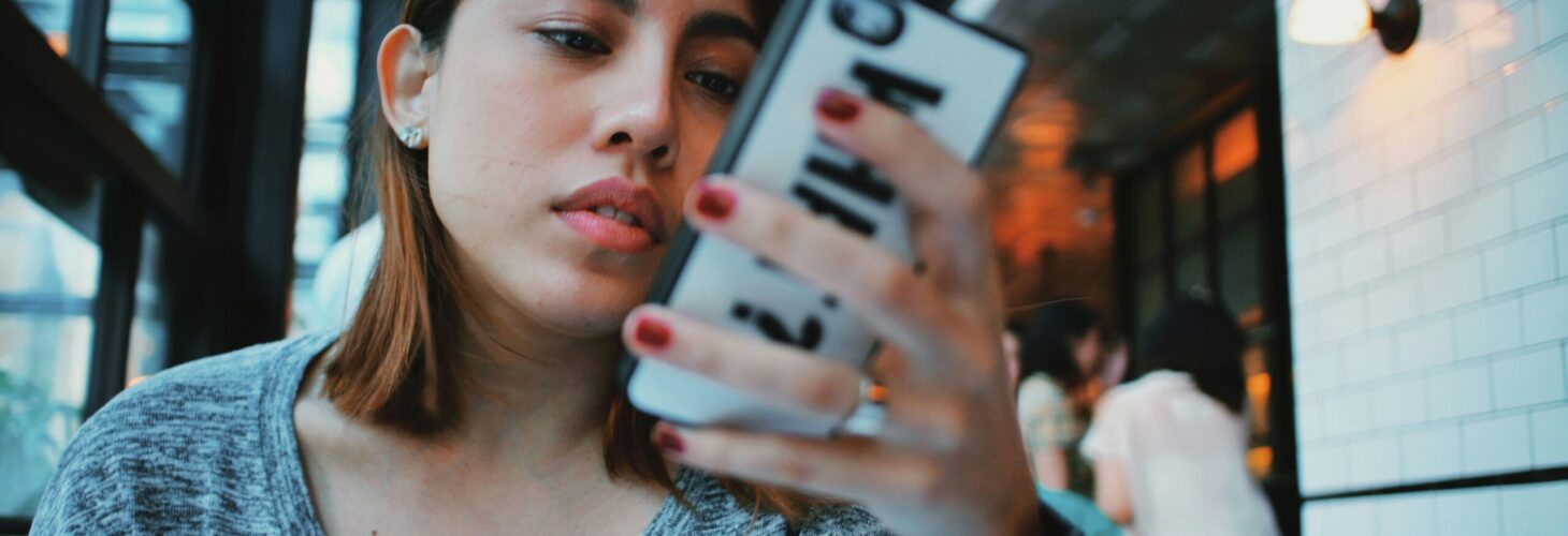 person short brown hair searching on phone in cafe