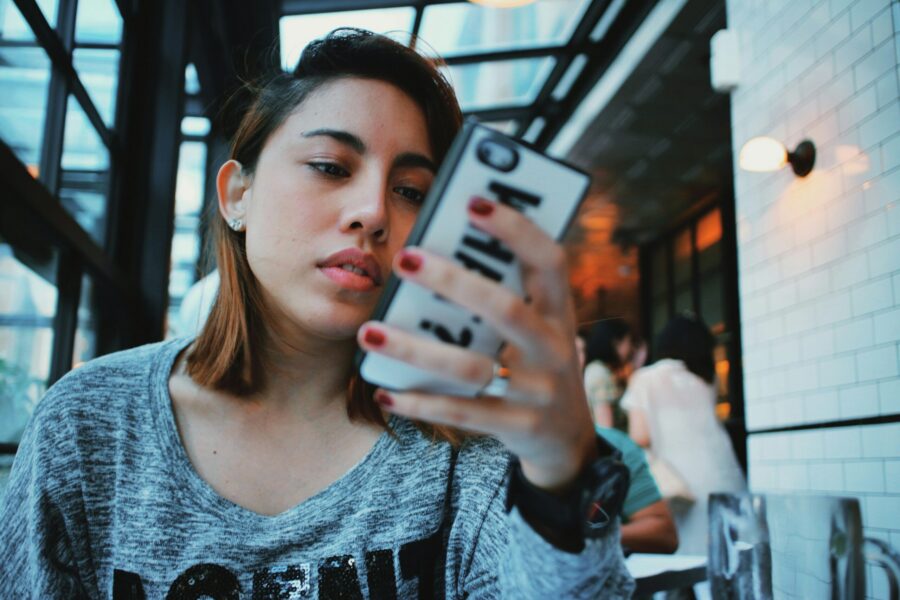 person short brown hair searching on phone in cafe