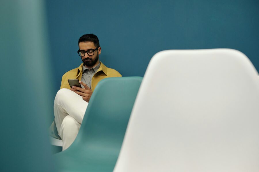 man glasses on phone waiting in waiting room chair