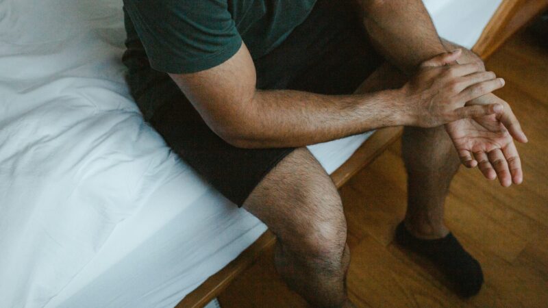 man pain bed side corssing hands