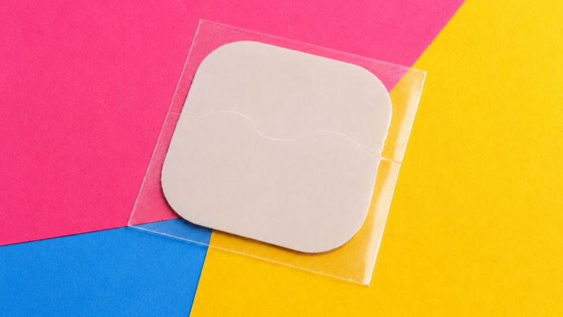 Contraceptive patch on a pink, yellow and blue background