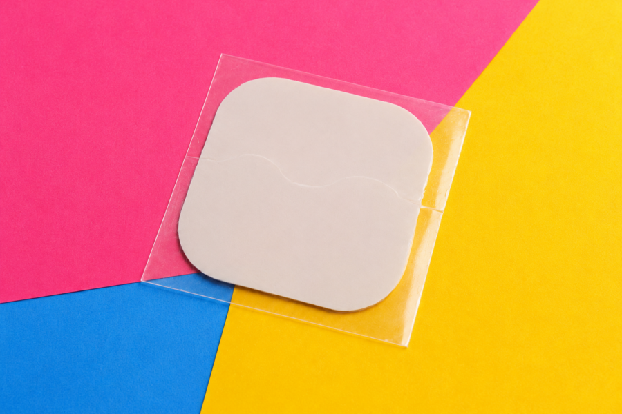 Contraceptive patch on a pink, yellow and blue background